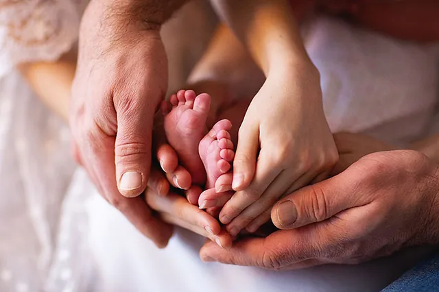 Hände der Eltern halten Kinderfüsschen