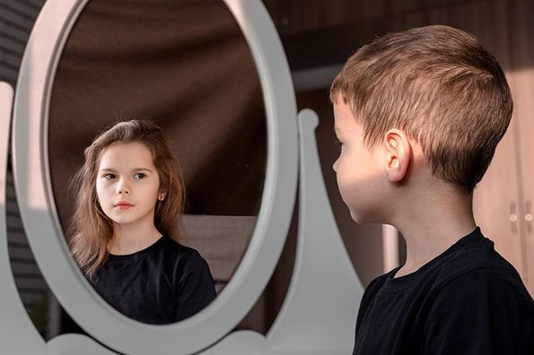 Junge sieht Mädchen im Spiegel - Geschlechtsidentität